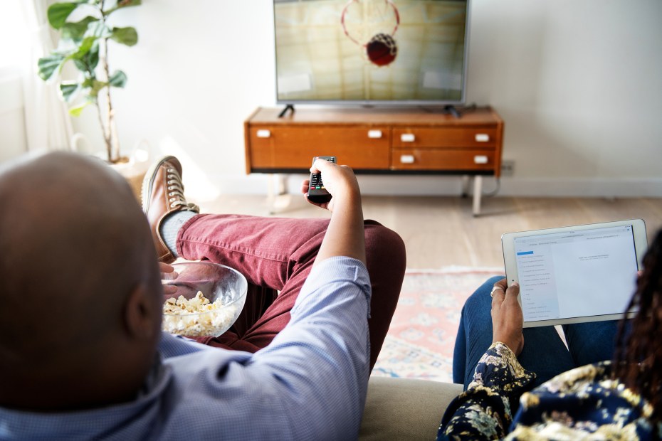 A couple watch a basketball game together.