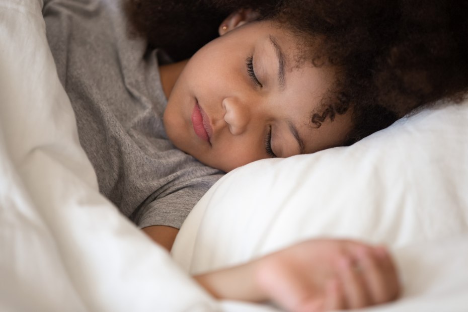 A young child sleeping in white sheets.