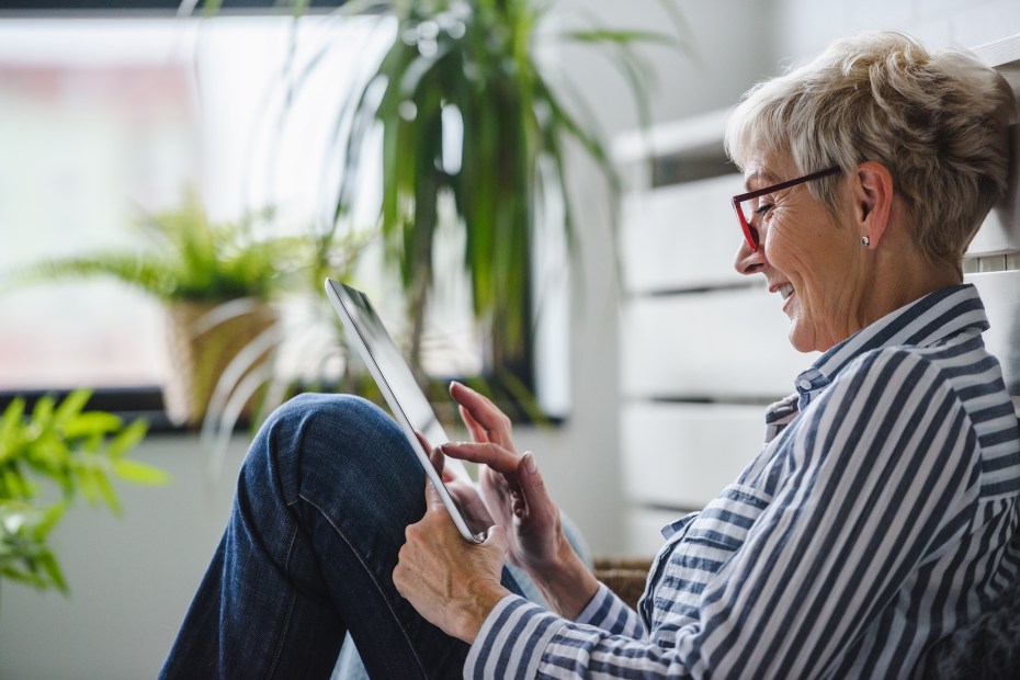 A woman sits on the floor with a tablet.