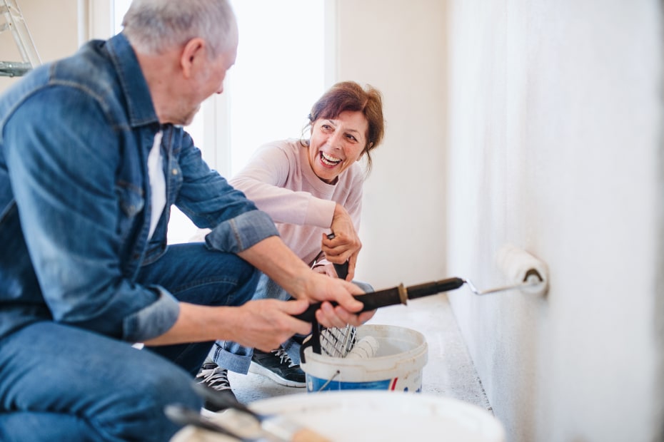 Senior couple paint a wall.