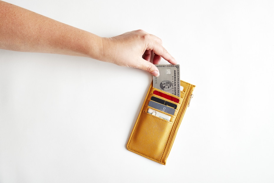 woman's hand places an American Express card in a yellow wallet