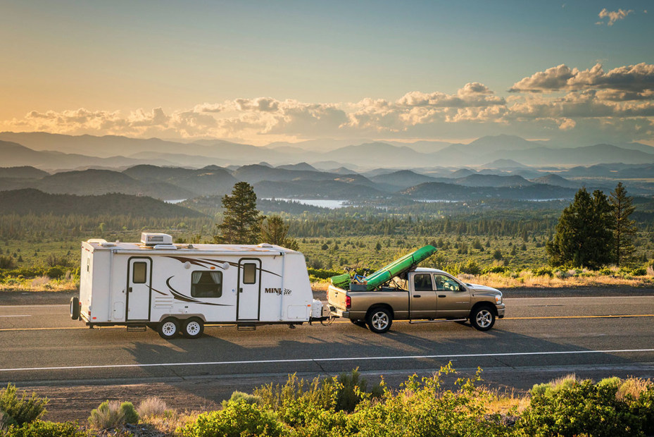 Truck towing an RV trailer with kayaks in the back.