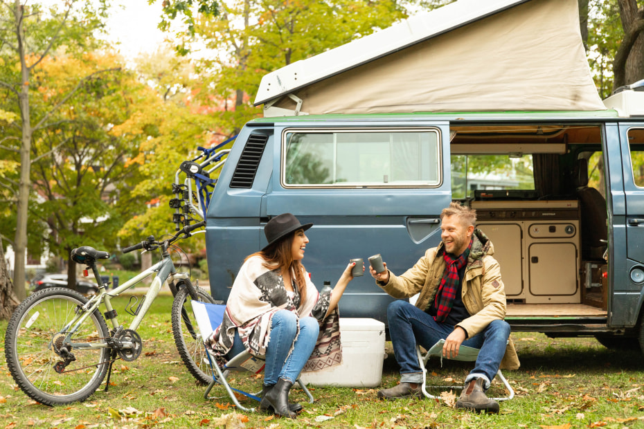 A couple toasts outside of their vintage camper van.