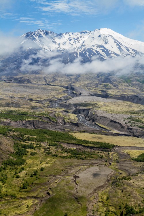 snowcapped Mount St. Helens looms in background as melted runoff channels down through the surrounding terrain