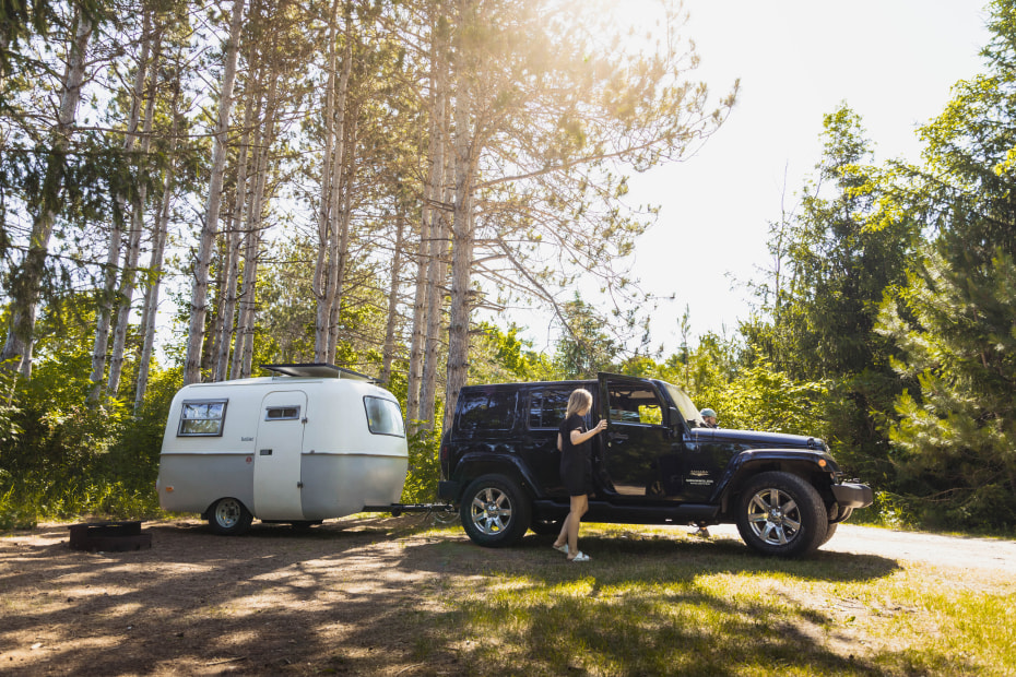 A woman guides a driver backing up a camping trailer.