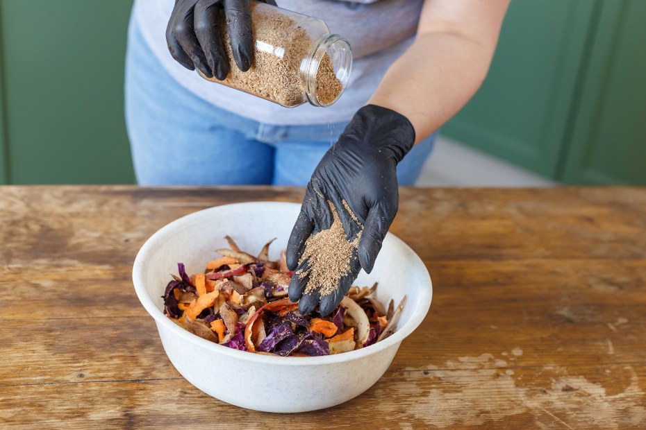 A woman mixes a starter culture into food scraps.