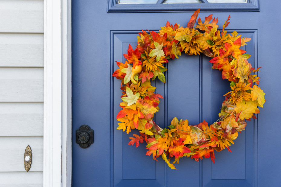 A wreath of dried leaves hanging on a blue door.