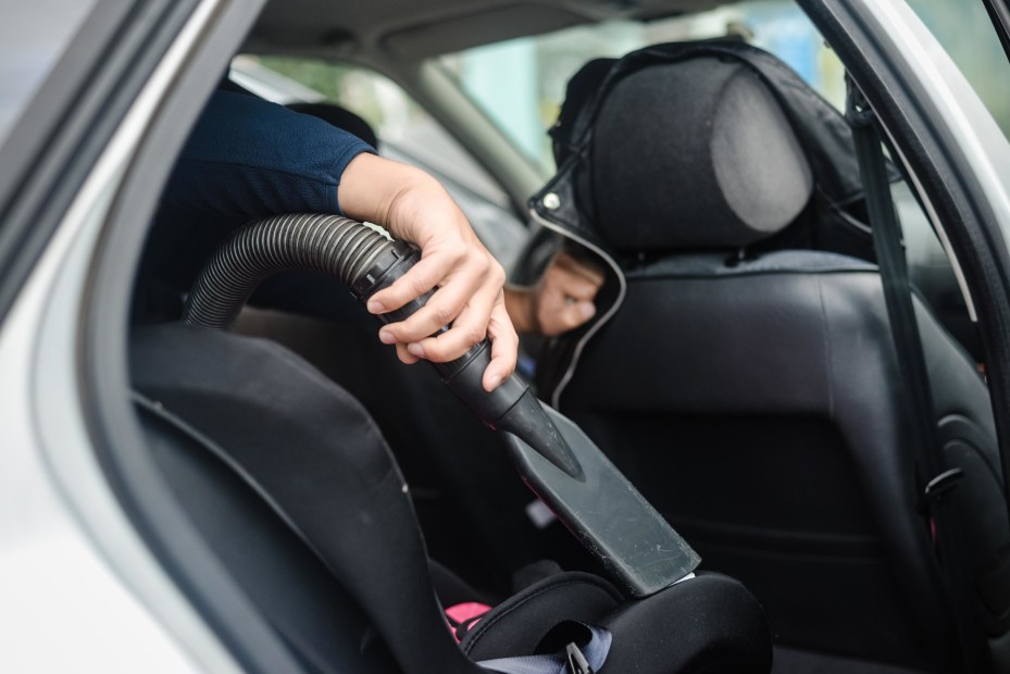 A person vacuums a car seat.