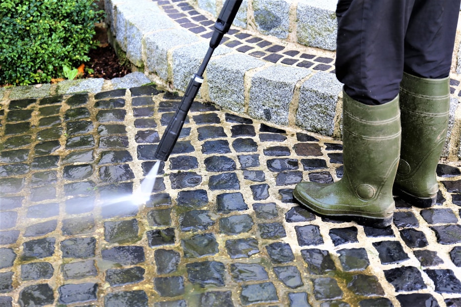 A homeowner pressure washes their front walkway.
