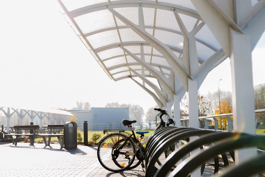 Two bikes locked to a covered bike rack in a park.