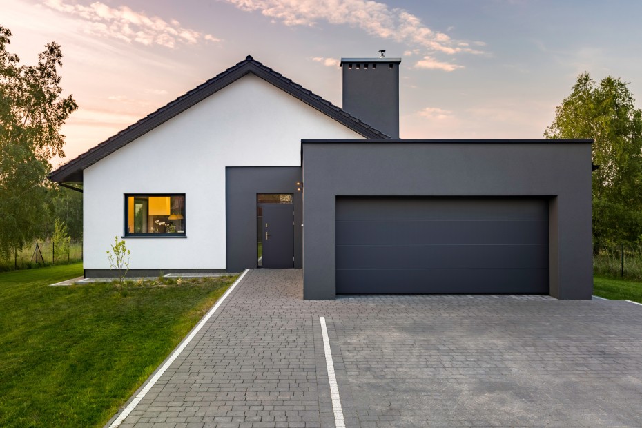 modern gray and white home exterior at sunset with long driveway and lawn