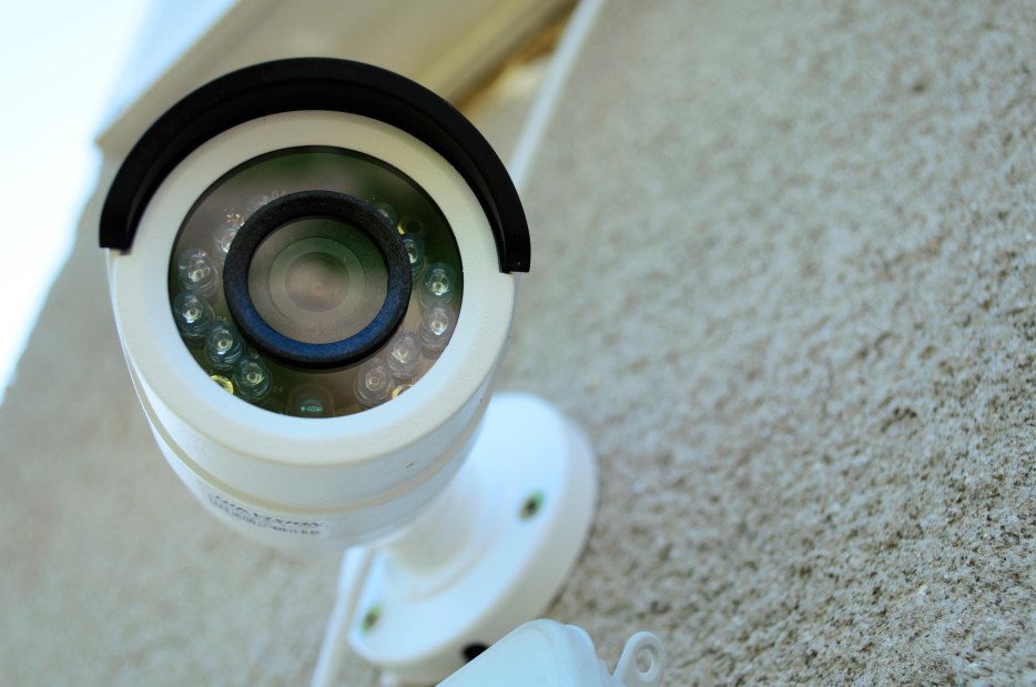 close up of a white home security camera mounted to an exterior wall