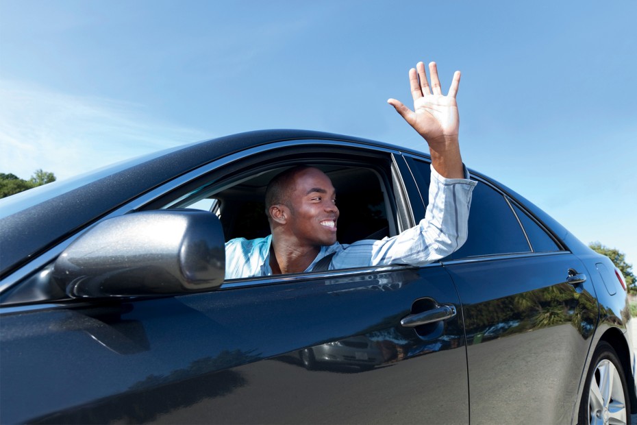 A driver waves thank you through the open window.