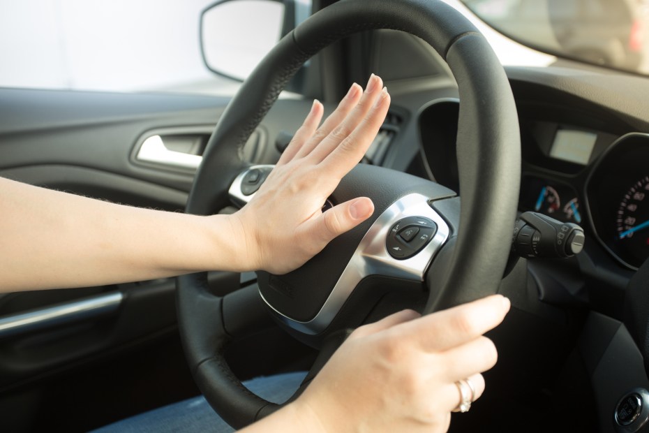 driver honks horn with left hand while right hand holds wheel at three position