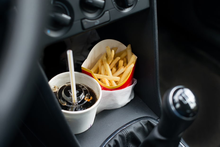 Fast food soda and fries in a car's cupholders.
