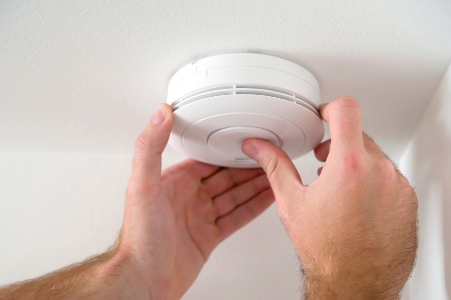 A man installs a carbon monoxide alarm