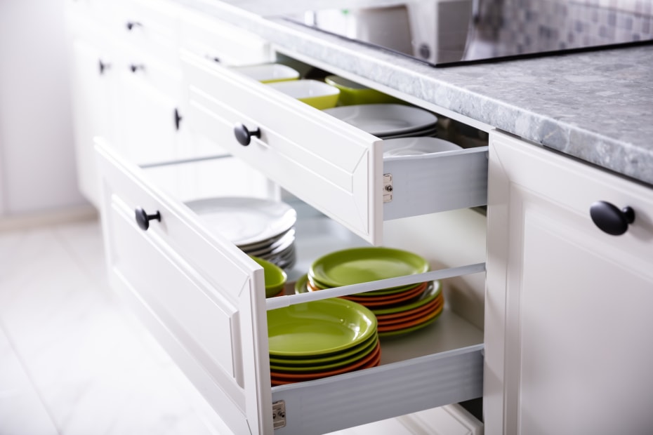 white kitchen drawers open to reveal colorful plateware
