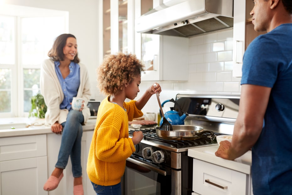 A girl cooks with her parents.