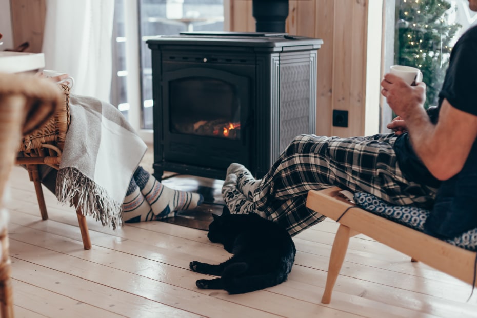 A couple and their cat sit in front of a gas stove.