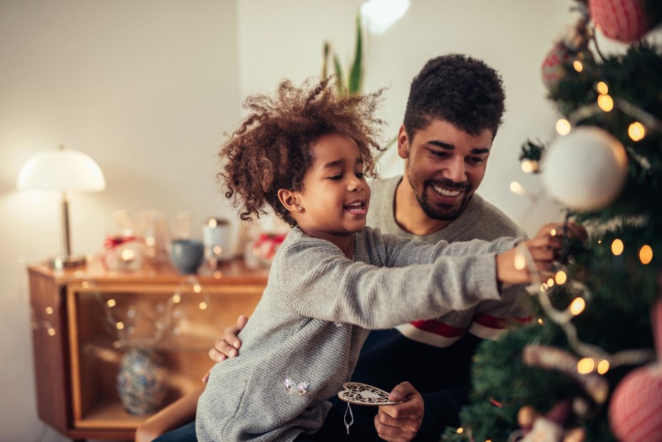 Cute girl decorating Christmas tree with dad.