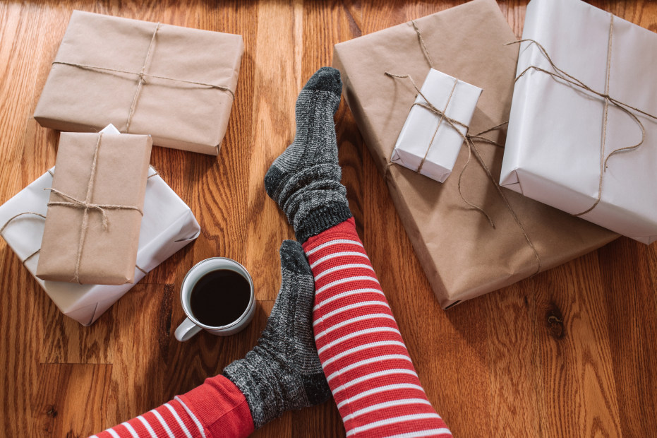 legs in christmas jammies with a cup of coffee and brown-paper-wrapped presents