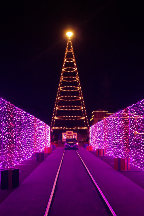 A car drives through a purple light display at San Jose's Christmas in the Park.