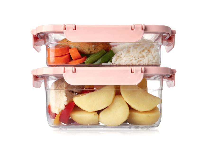 Pair of clear plastic kitchen containers with pink lids, stacked, containing prepared food on white background