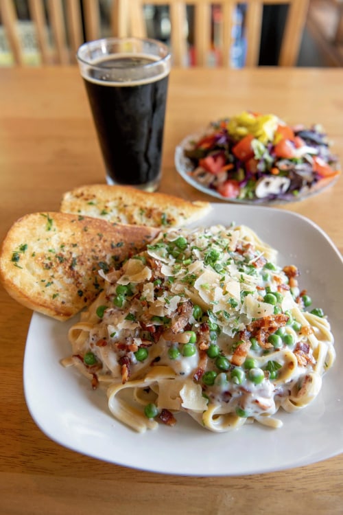 plate of pasta carbonara served with garlic bread, side salad and a pint of wintry stout at R Spot in Sisters, Oregon