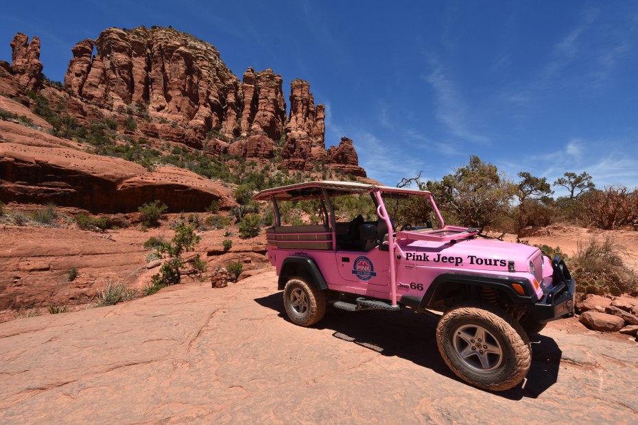 A pink Jeep from Pink Adventure Tours parked on a red rock route.
