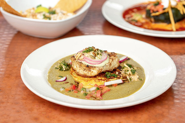 Trio of dishes with halibut served in mole verde featured front and center at Elote Cafe.