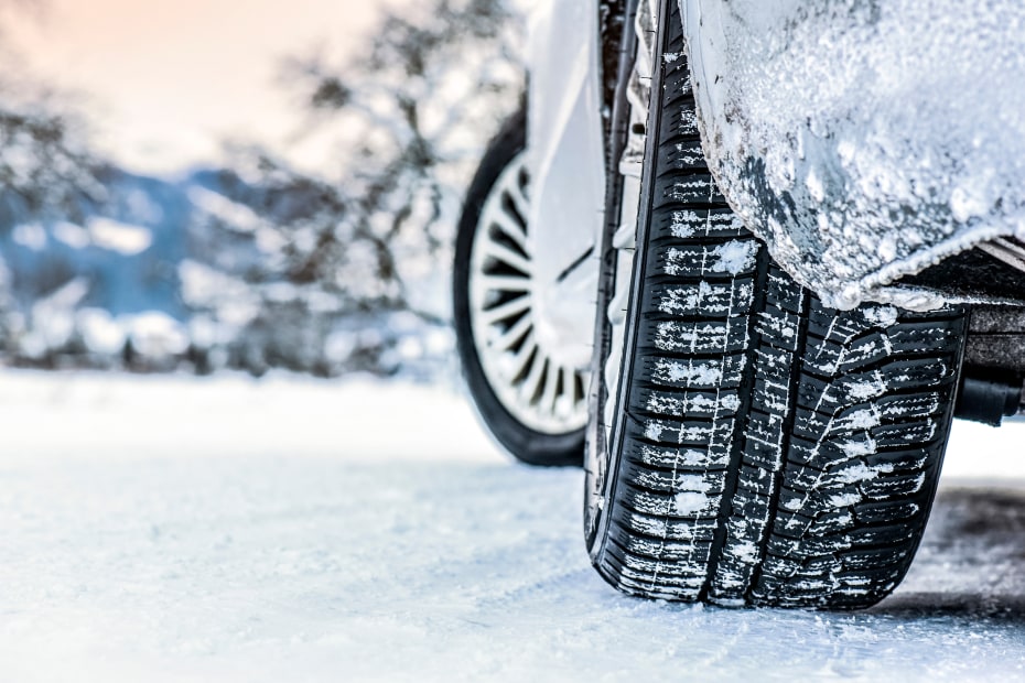 Tire with snow in the treads on a snowy road.