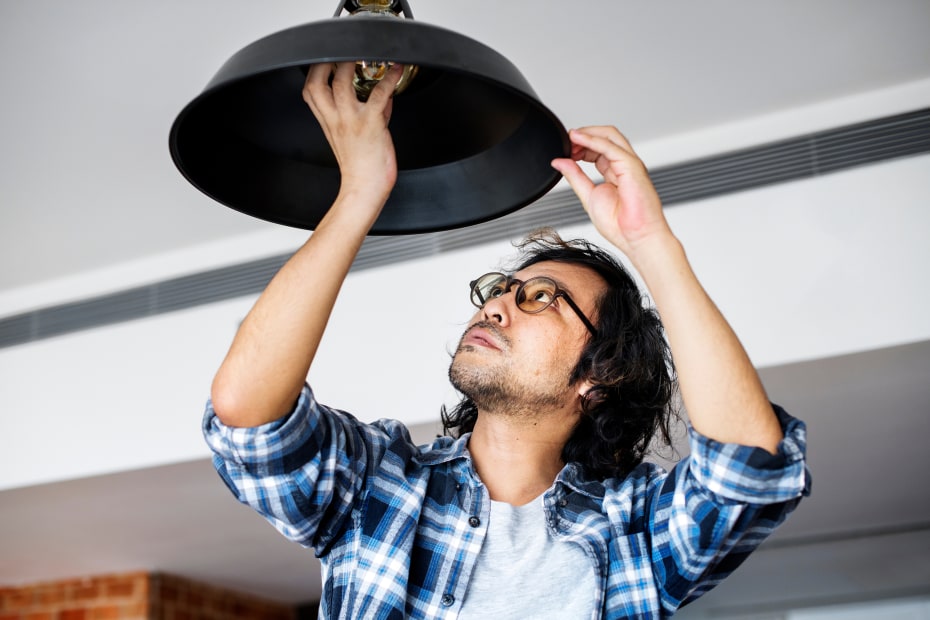 AAA Member screws an LED light bulb into a pendant light.