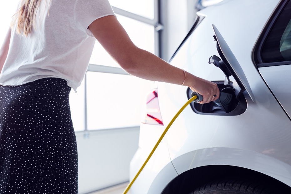 A woman plugs in an electric car charger inside her garage.
