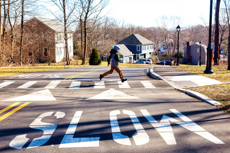 A young boy runs across a crosswalk.