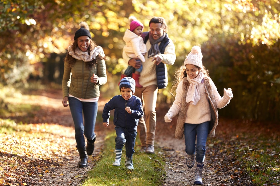 A family runs down a tree-lined path together.