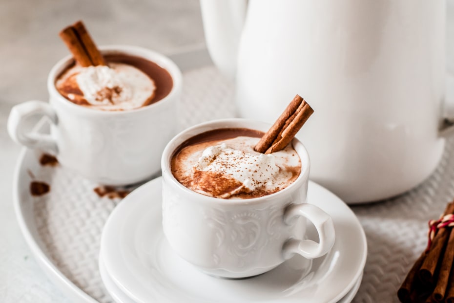 Hot chocolate with cinnamon, chilli, and whipped cream in white mugs.