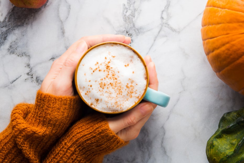 Hands hold a mug of homemade pumpkin spice latte.