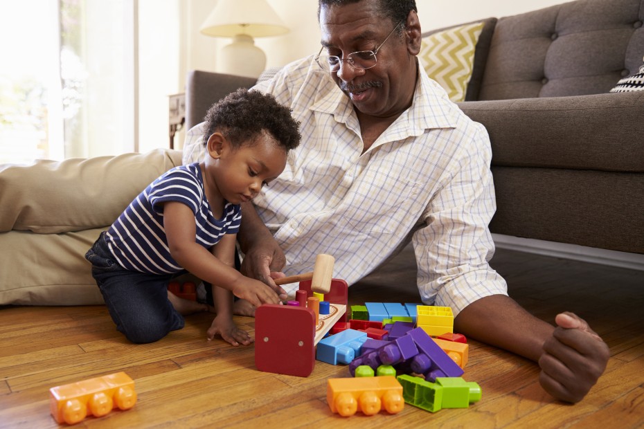 A grandpa plays on the floor with his grandchild.