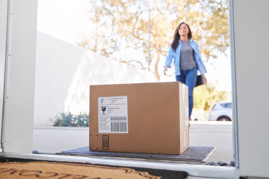 A woman walks up to a package on her porch.