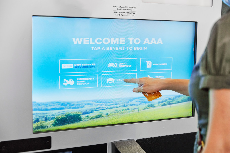 A woman uses a touch screen inside a AAA branch.