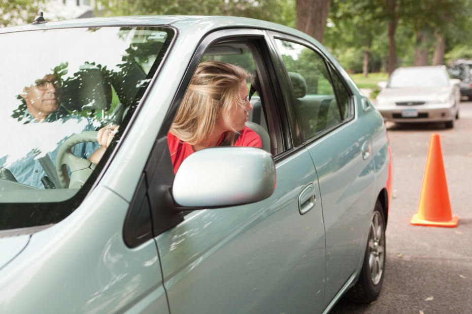 A teen practices reversing a car with her dad.