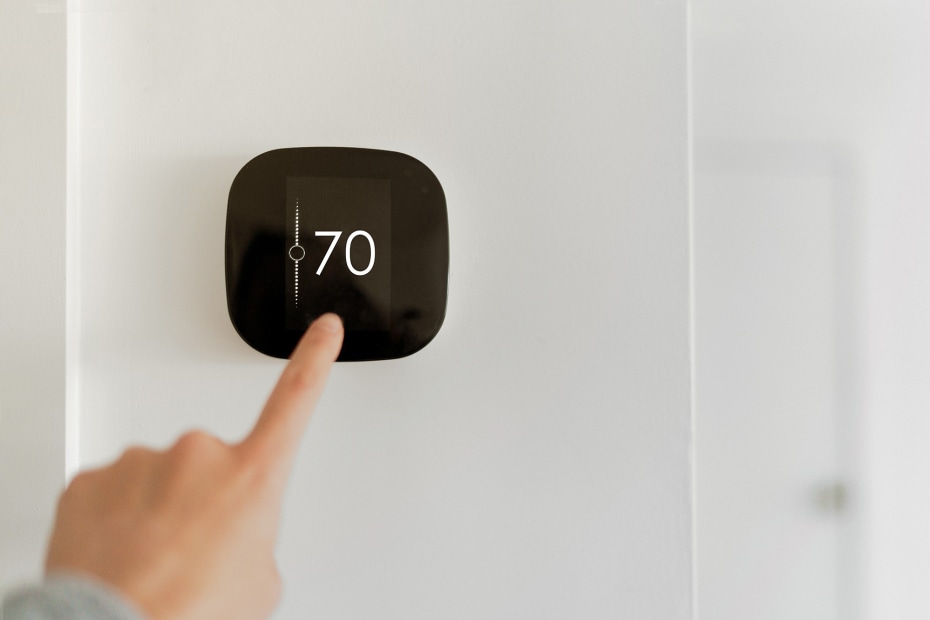 A person sets their smart thermostat.
