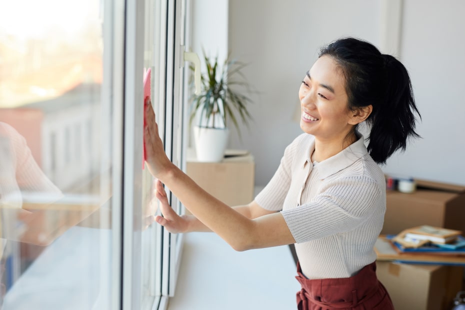 A woman cleans the inside of her windows.