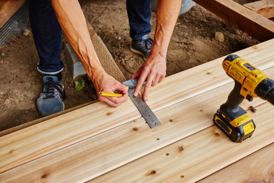 A deck builder installs planks on top of support joists.