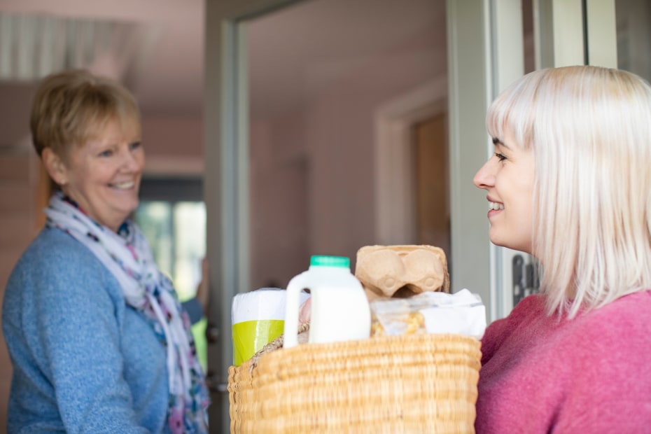 A woman brings her neighbor essential groceries.