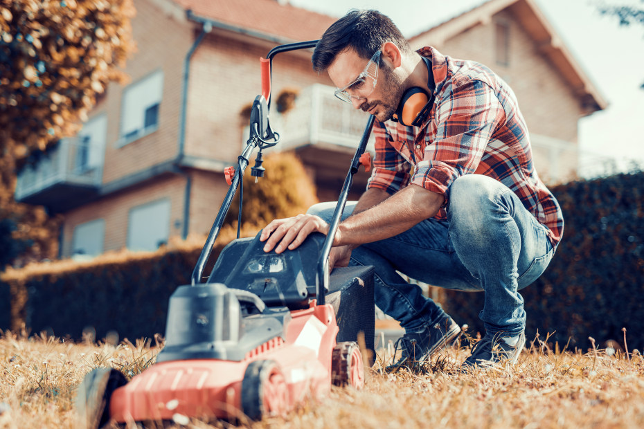 A man prepares his lawn mower.