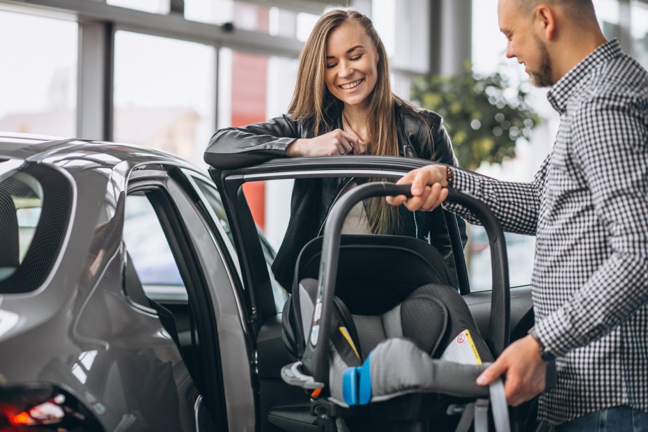 A couple test a car seat at the car dealership.