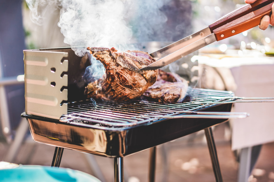 A person flips a steak on a grill.