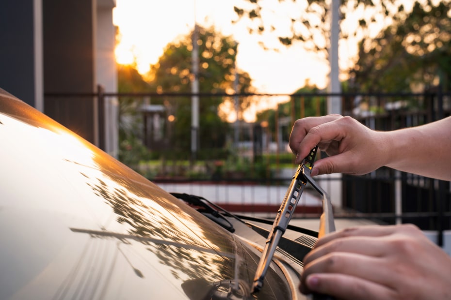 A driver replaces their windshield wipers.