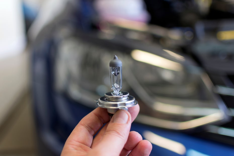 A man holds a car headlight bulb.